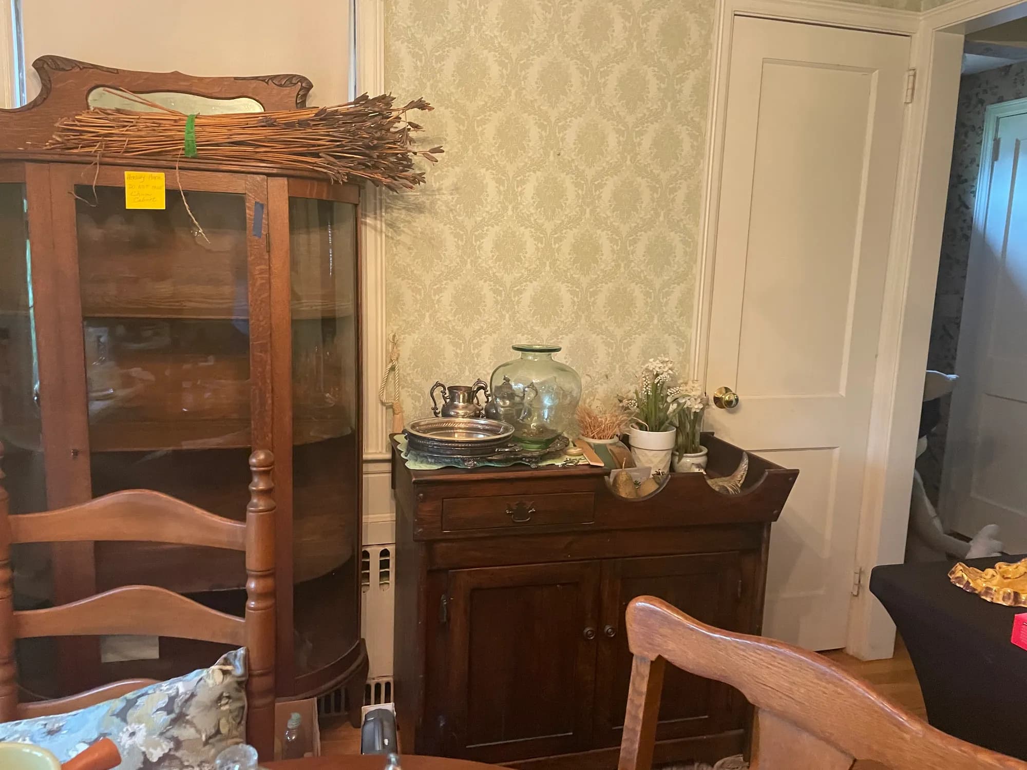 An estate dining room with an antique china cabinet, a silver tray, and glassware.