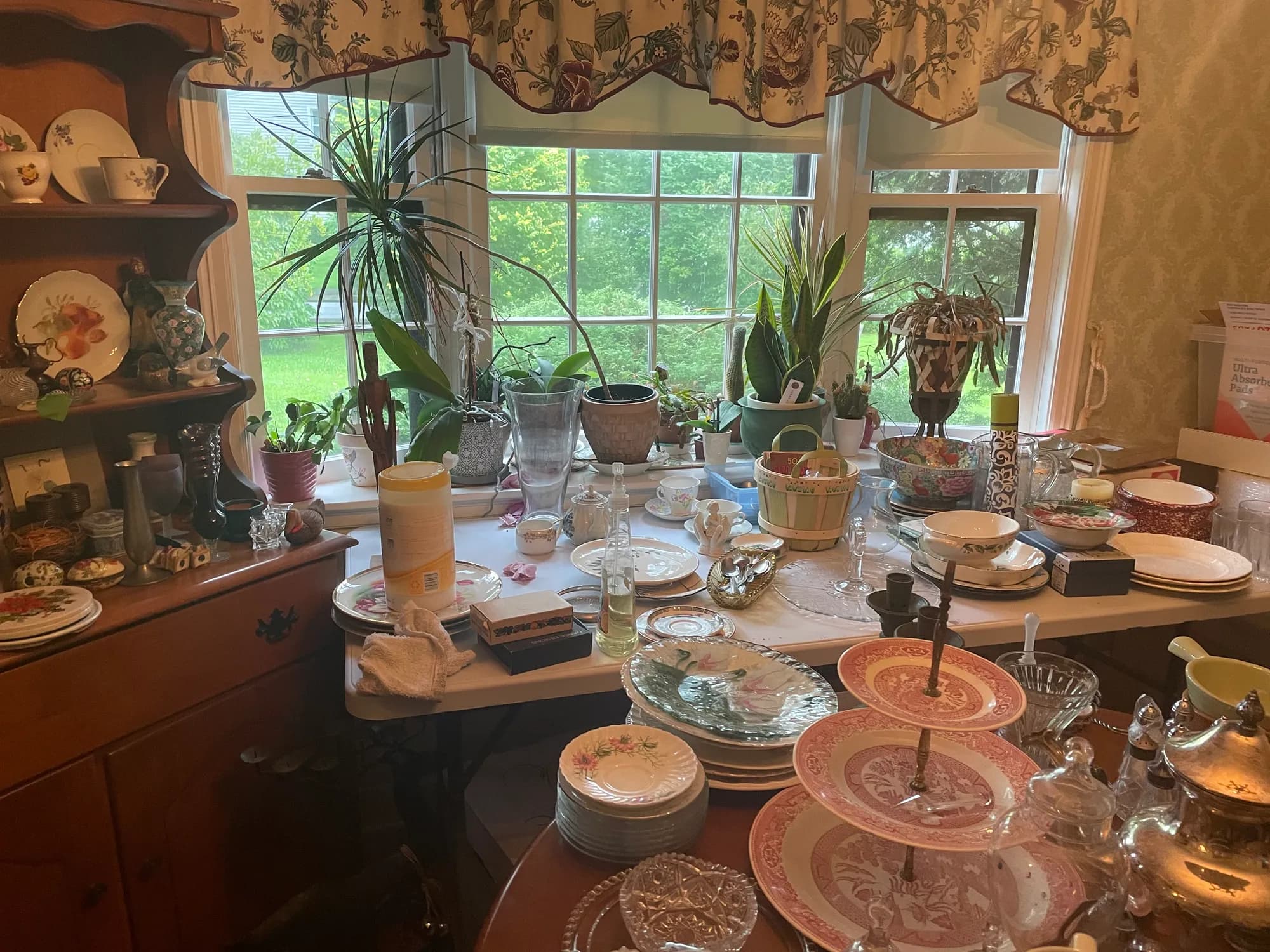 Hutch shelves filled with patterned china and glassware beside a window.