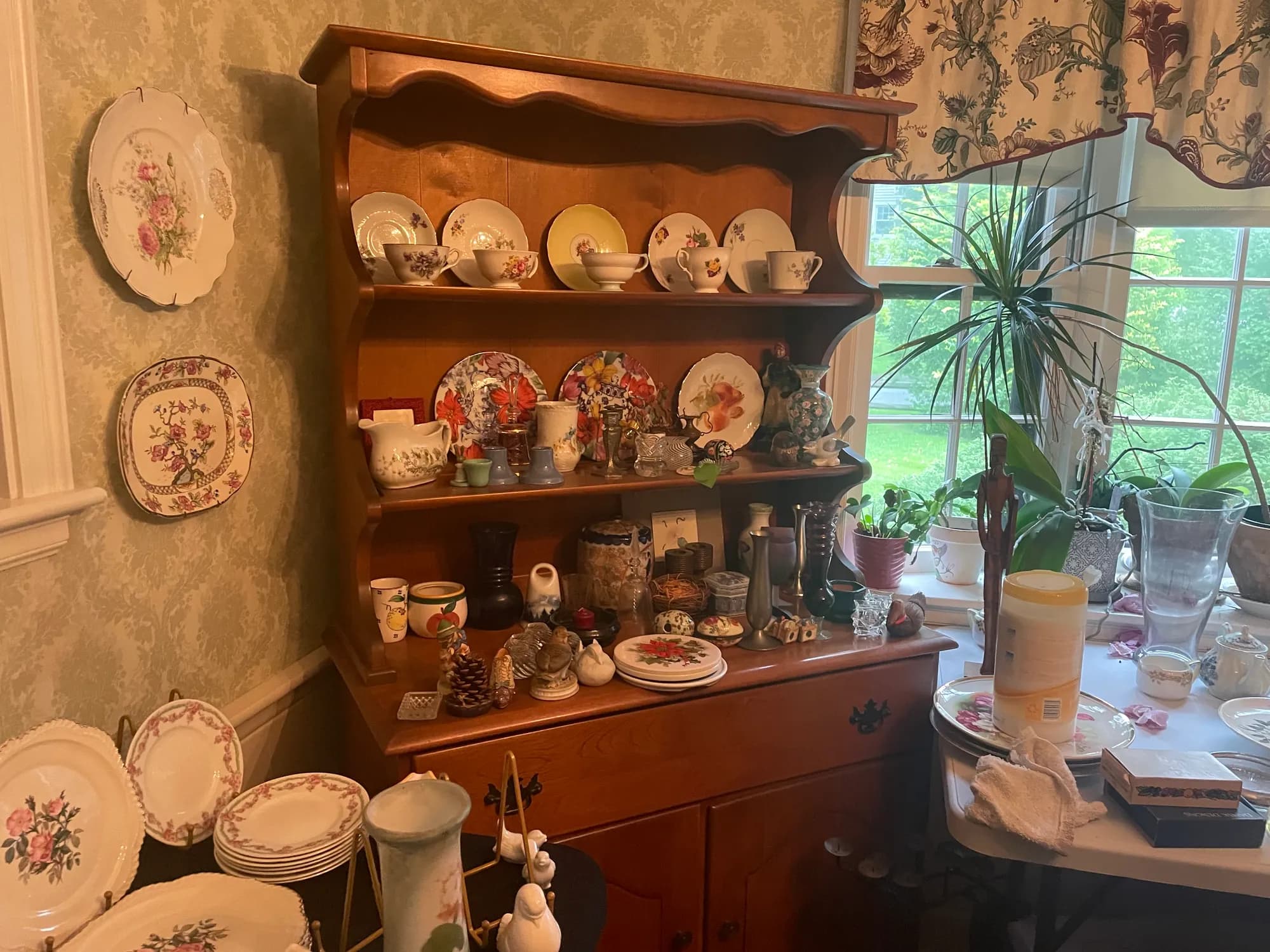 A corner cabinet displaying floral vintage china and teacups.