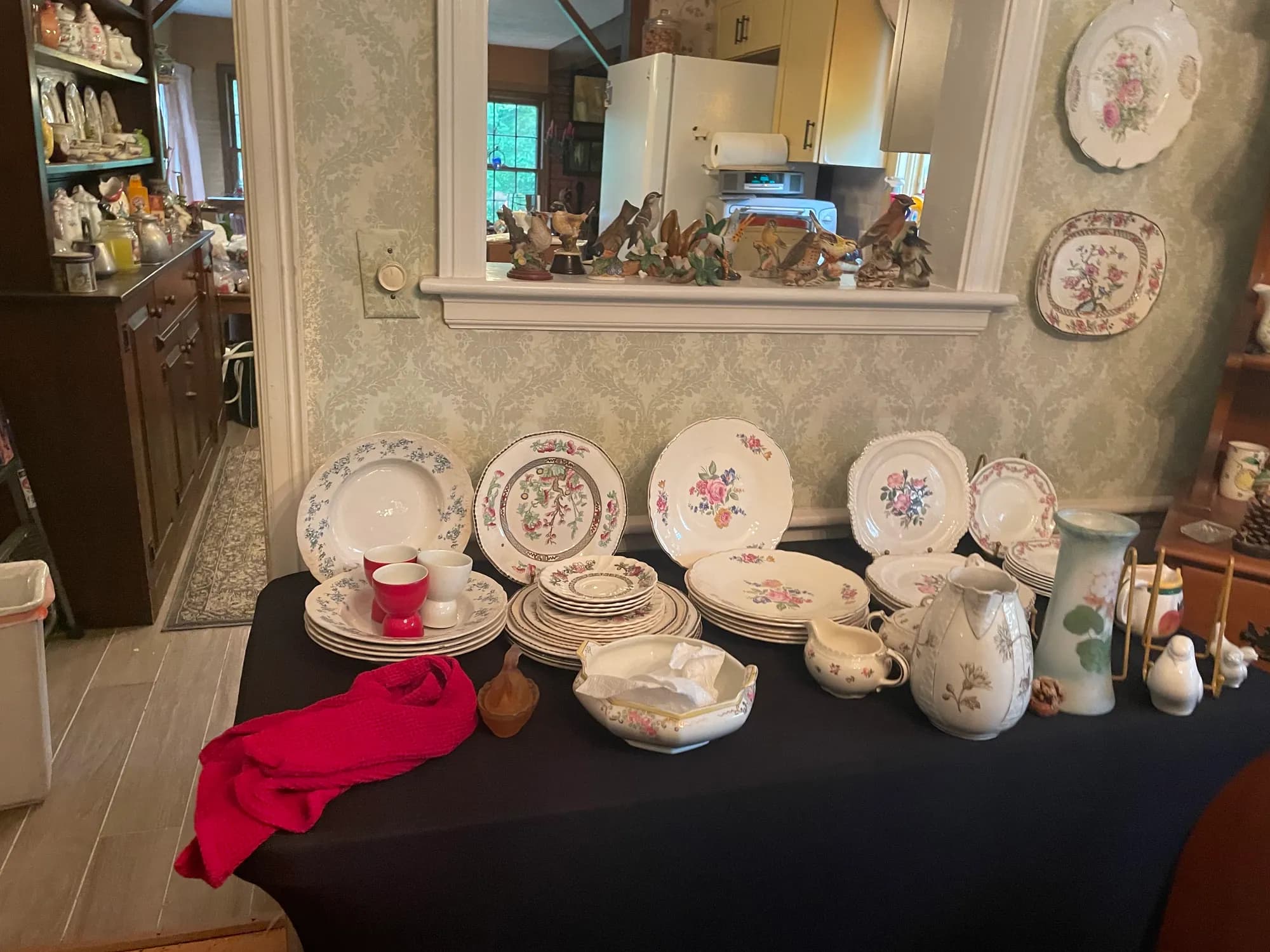 Floral china plates displayed on a wall above a hutch of dishes.