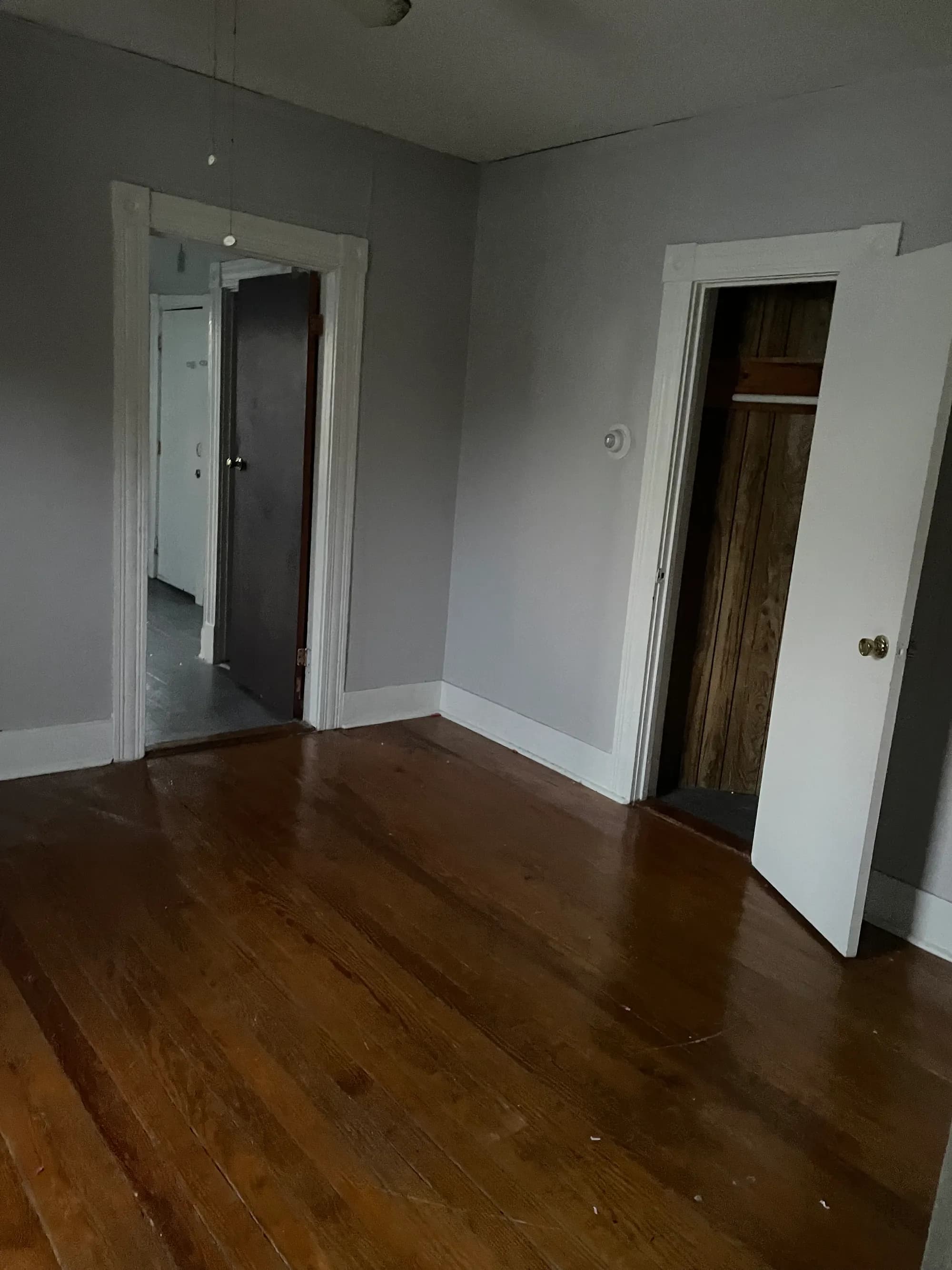 A cleared room with open doorways and a swept wood floor.