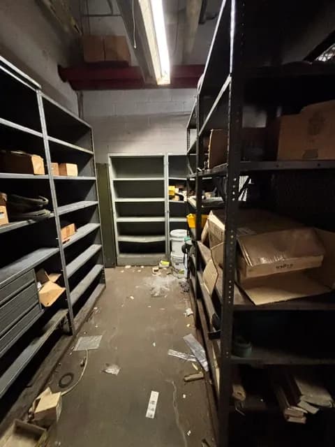 A storeroom with steel shelving and a few remaining boxes.