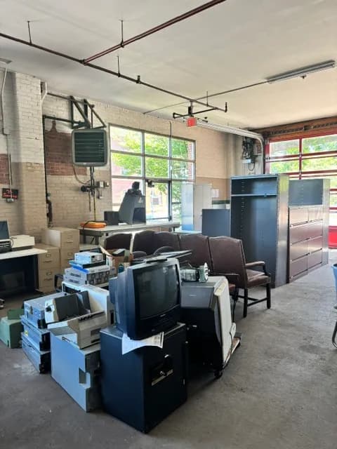 A commercial space being cleared, with office furniture, filing cabinets, and vintage monitors.