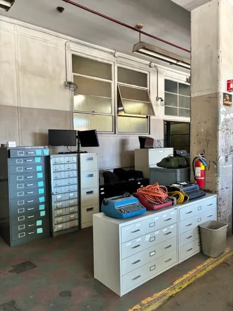 Filing cabinets, monitors, and office equipment staged for liquidation.