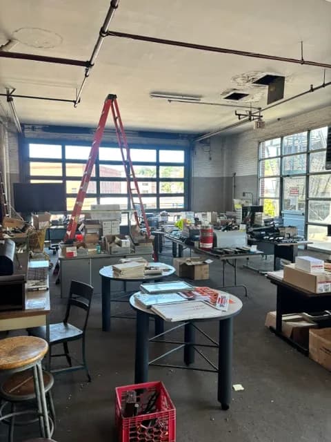 A bright industrial room with tables of goods staged for sale.
