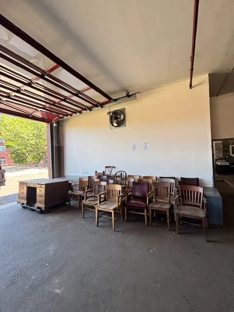 A cluster of antique wooden office chairs and a desk under a canopy.