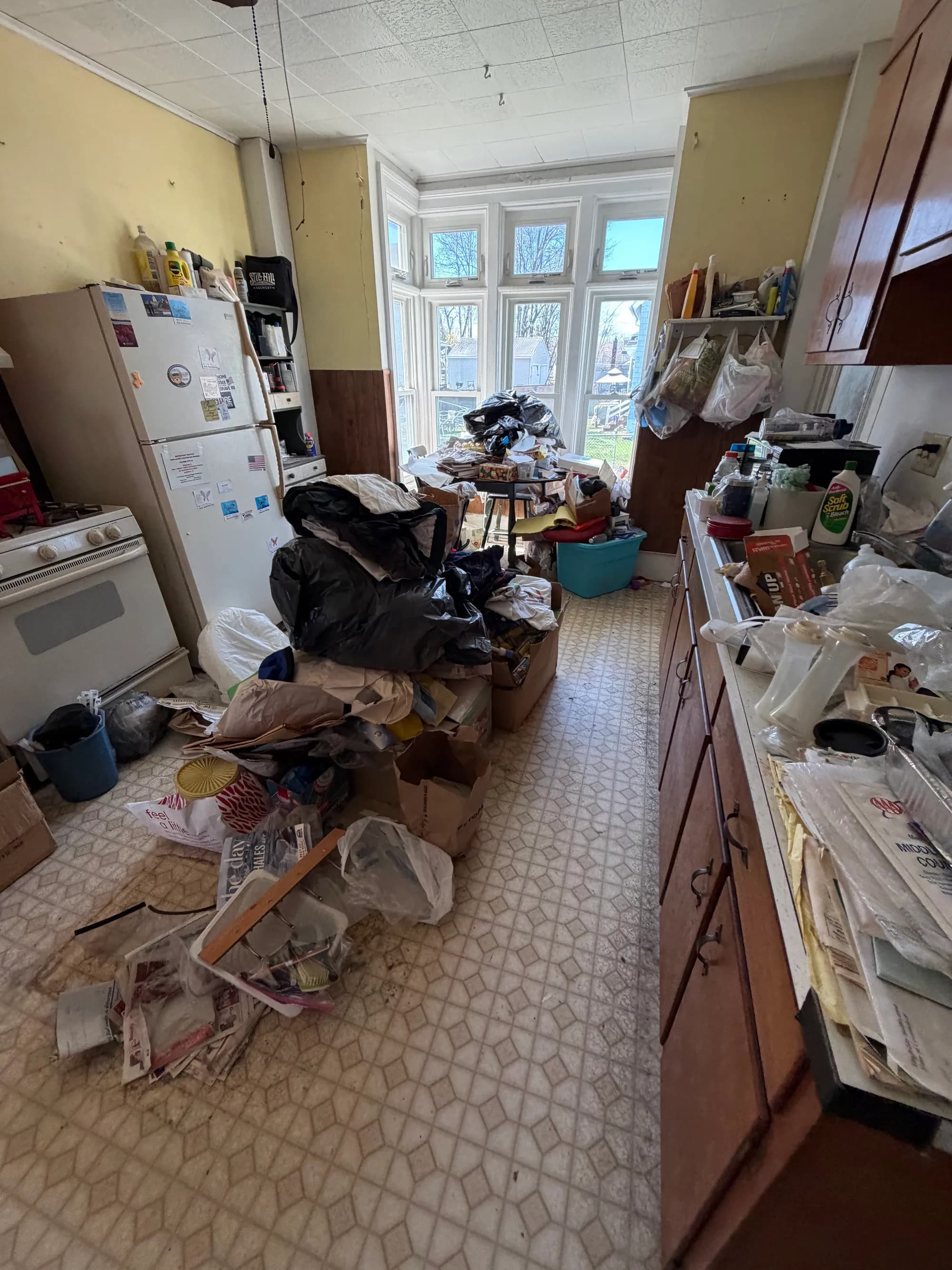 A cluttered kitchen filled with bags and boxes before a cleanout.