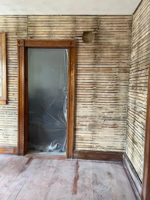 A room stripped to bare lath during a plaster removal.