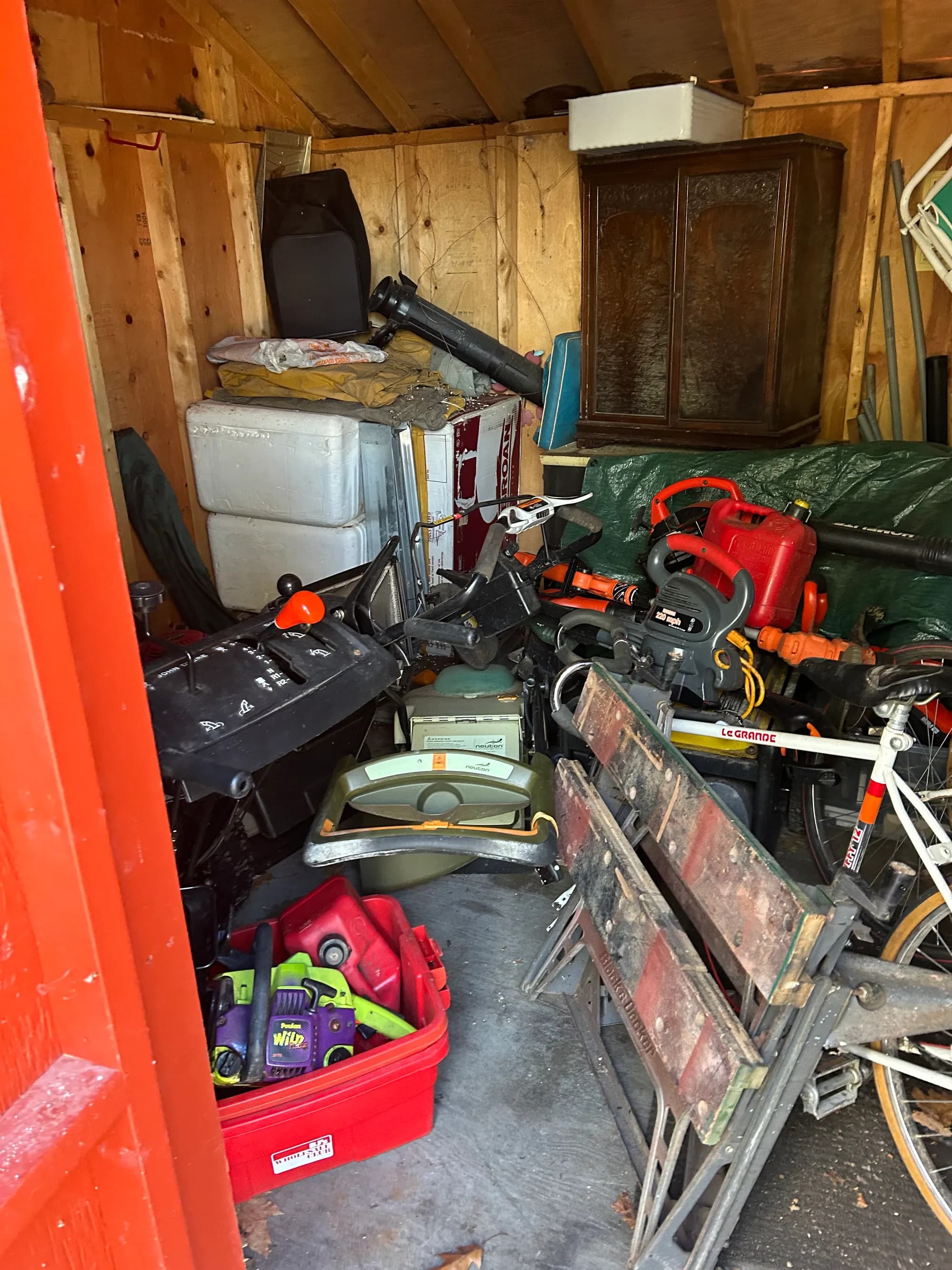 A storage shed packed with tools, ladders, and yard equipment.